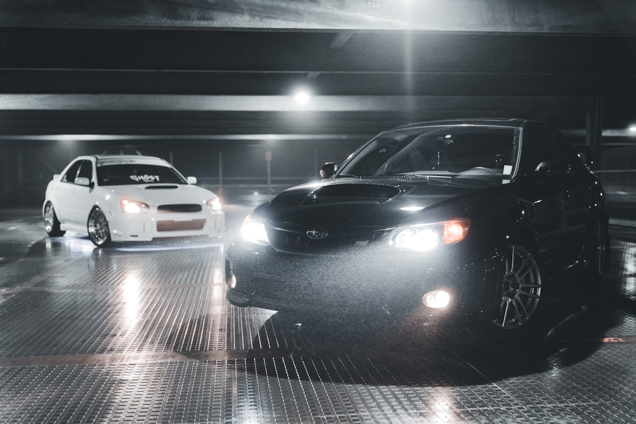 Two Subaru WRX cars, tuned and modified, in an underground parking garage.